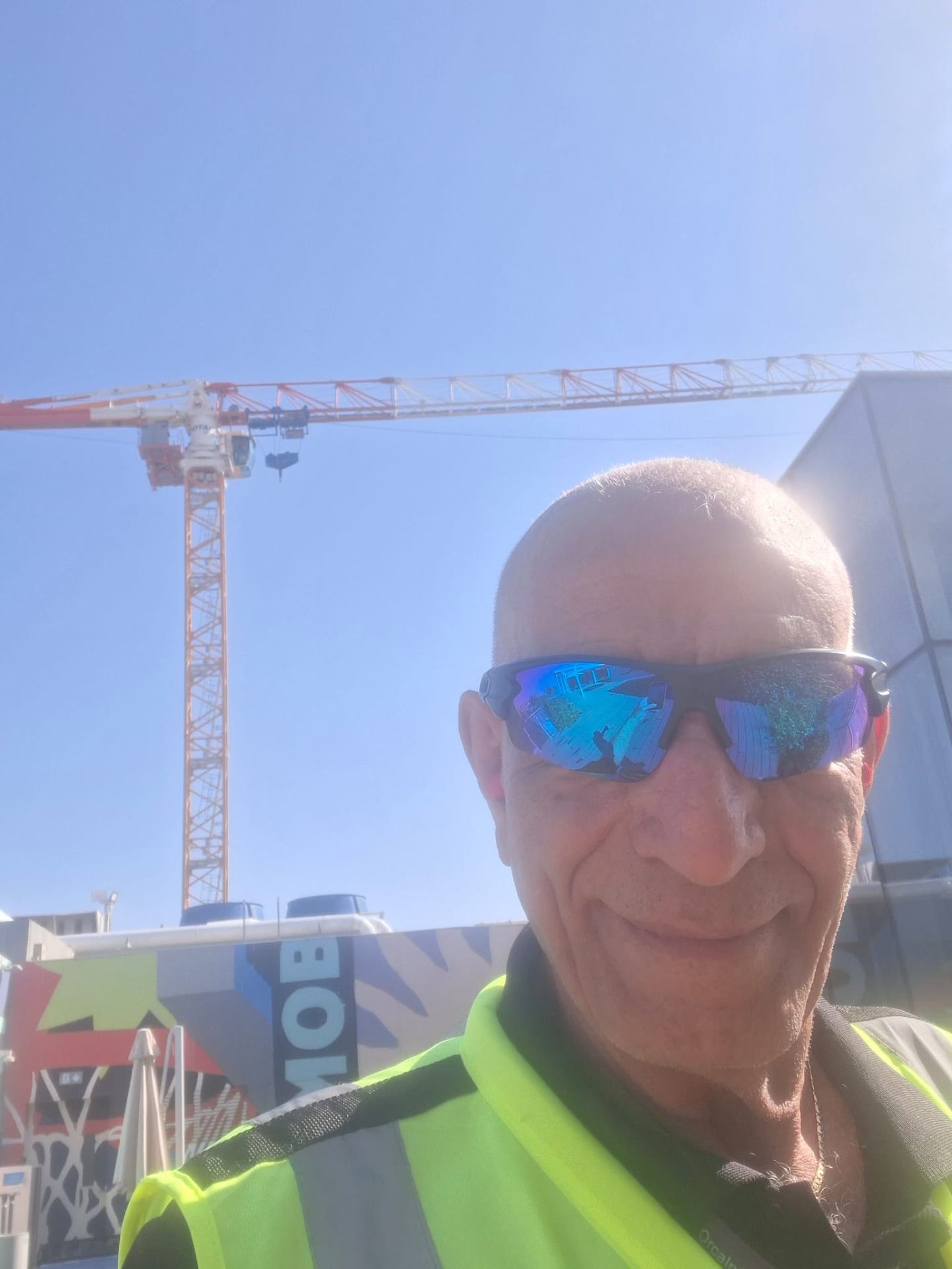 חנניה כהן באפוד זוהר באתר בנייה על רקע מנוף צריח